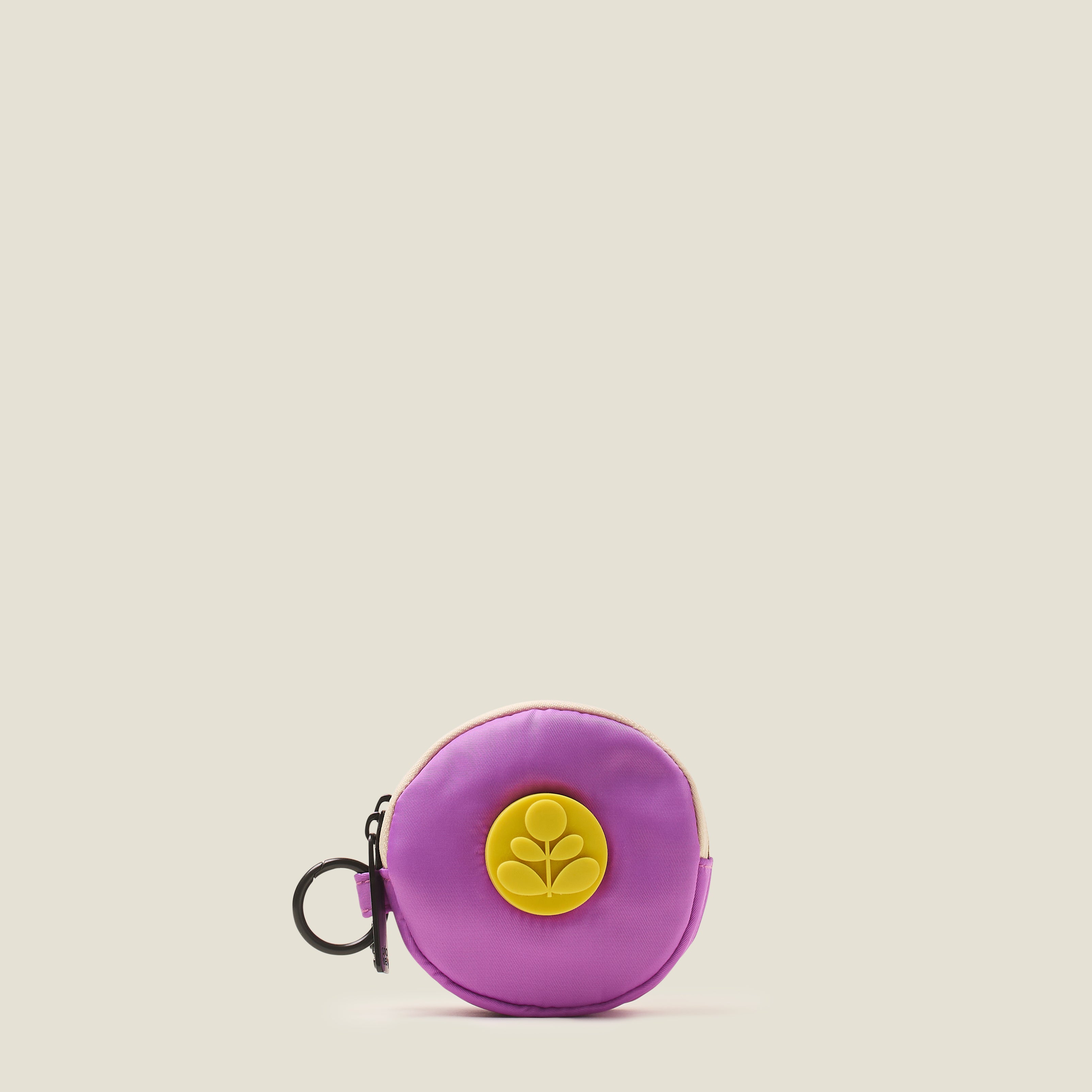 Lilac purple round coin purse with a rubber yellow Orla Kiely stem logo and ring clip on a beige background