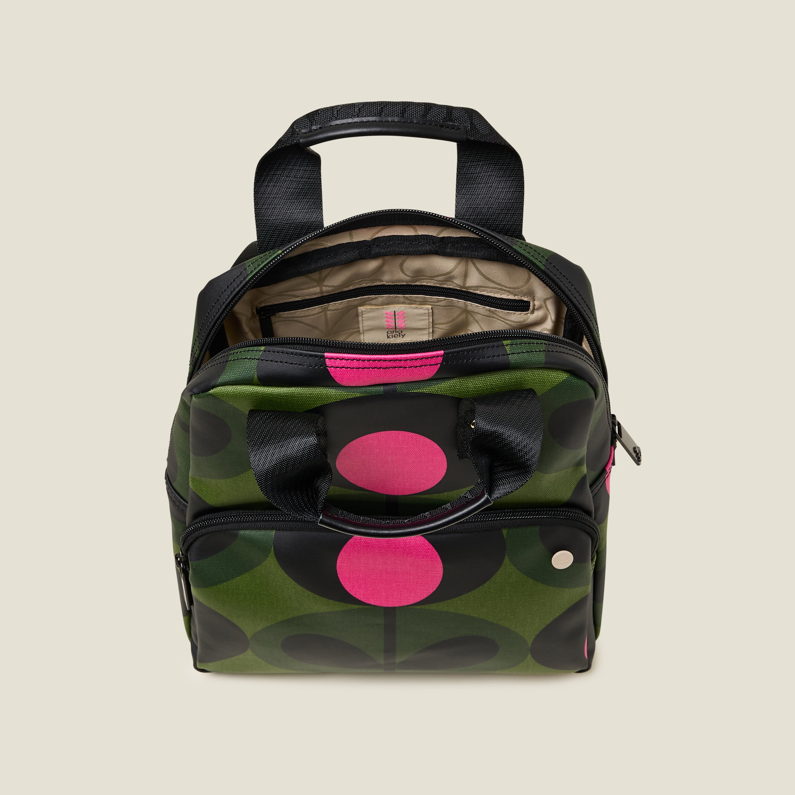 Inside view of Mini Lotta Backpack in a green stem print with bright pink dots, featuring a zipped inside pocket, and branded lining.