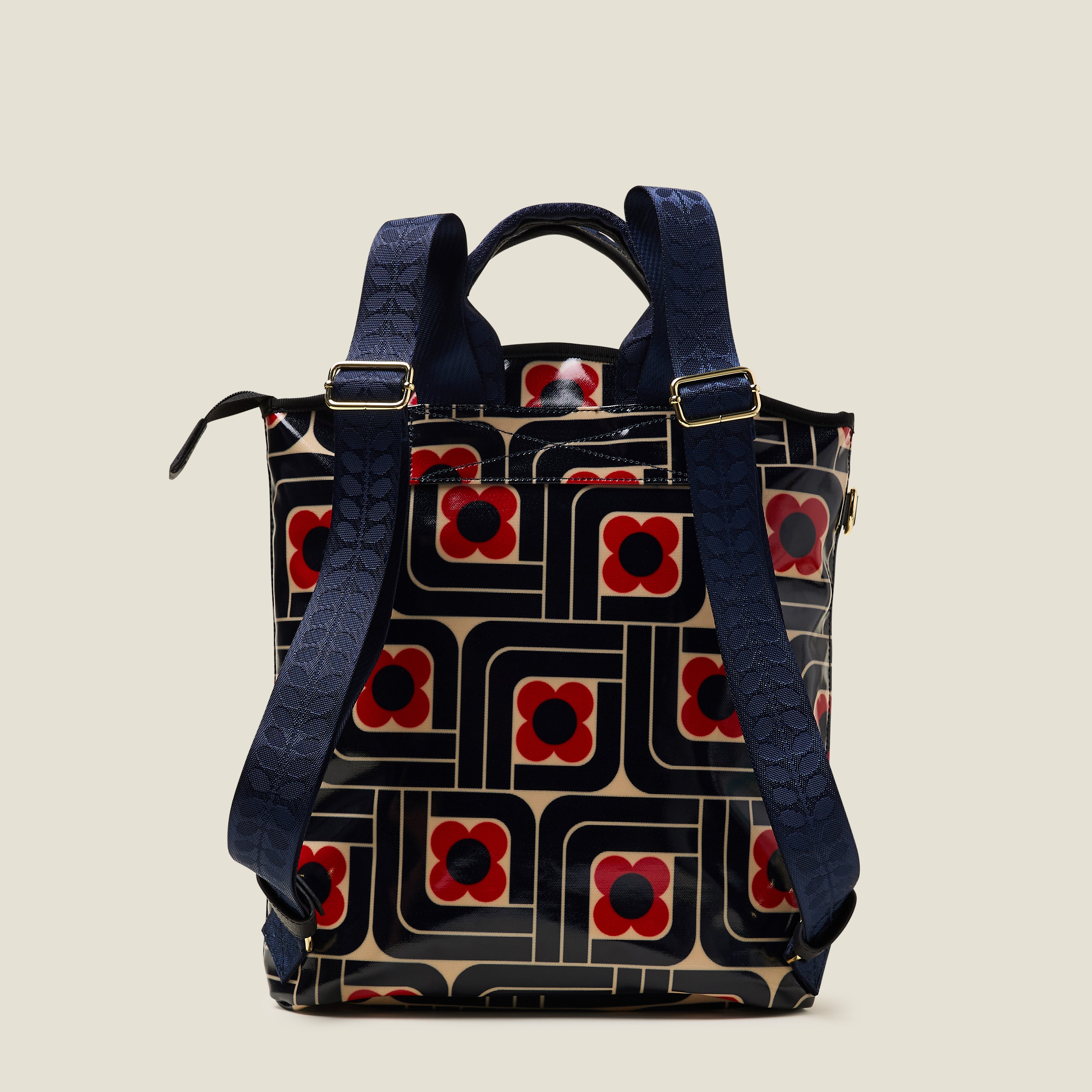 Back view of a women's backpack in a navy blue and red geometric floral pattern on a beige background.