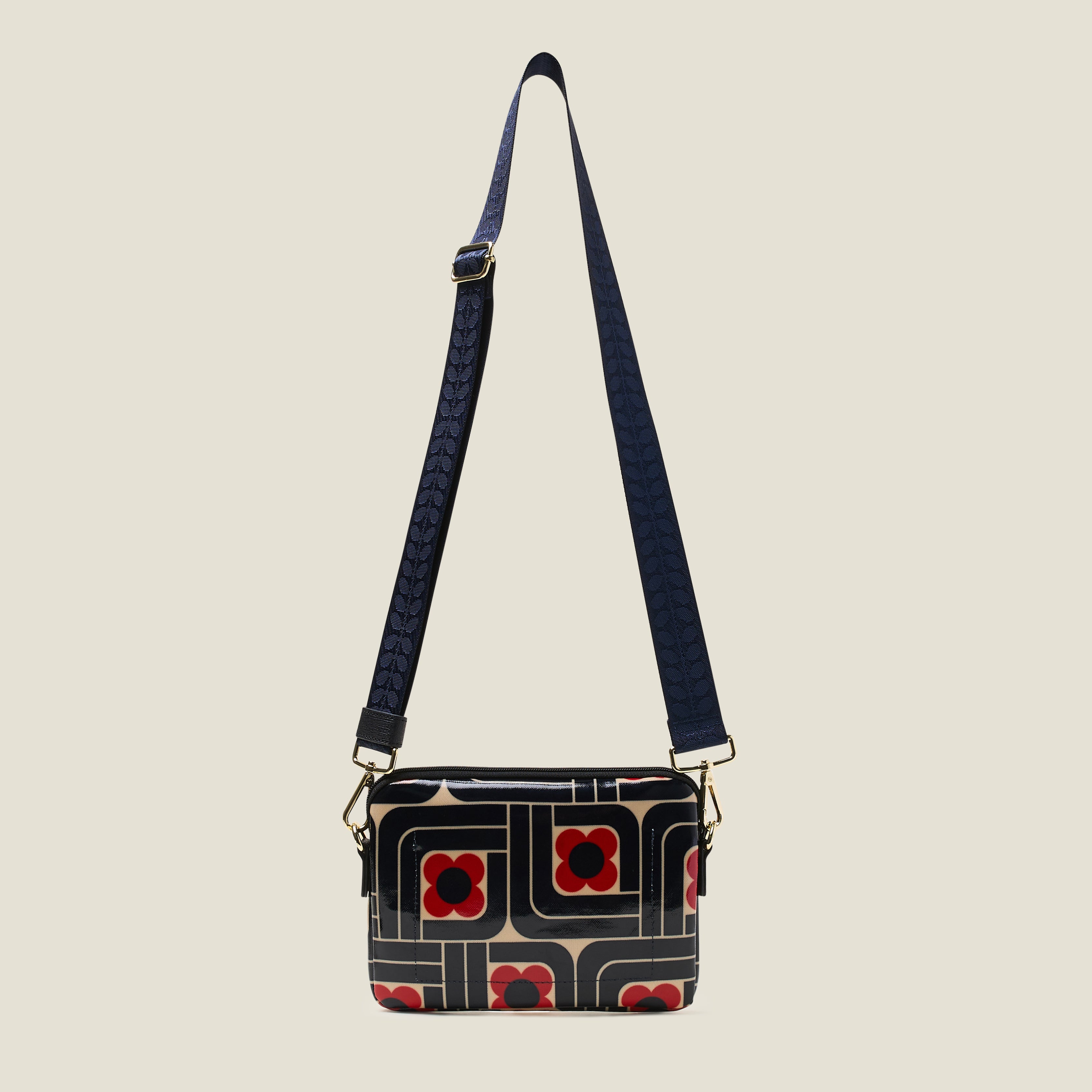 Front view of the slim crossbody patterned handbag in navy, red and cream with navy strap at full length.