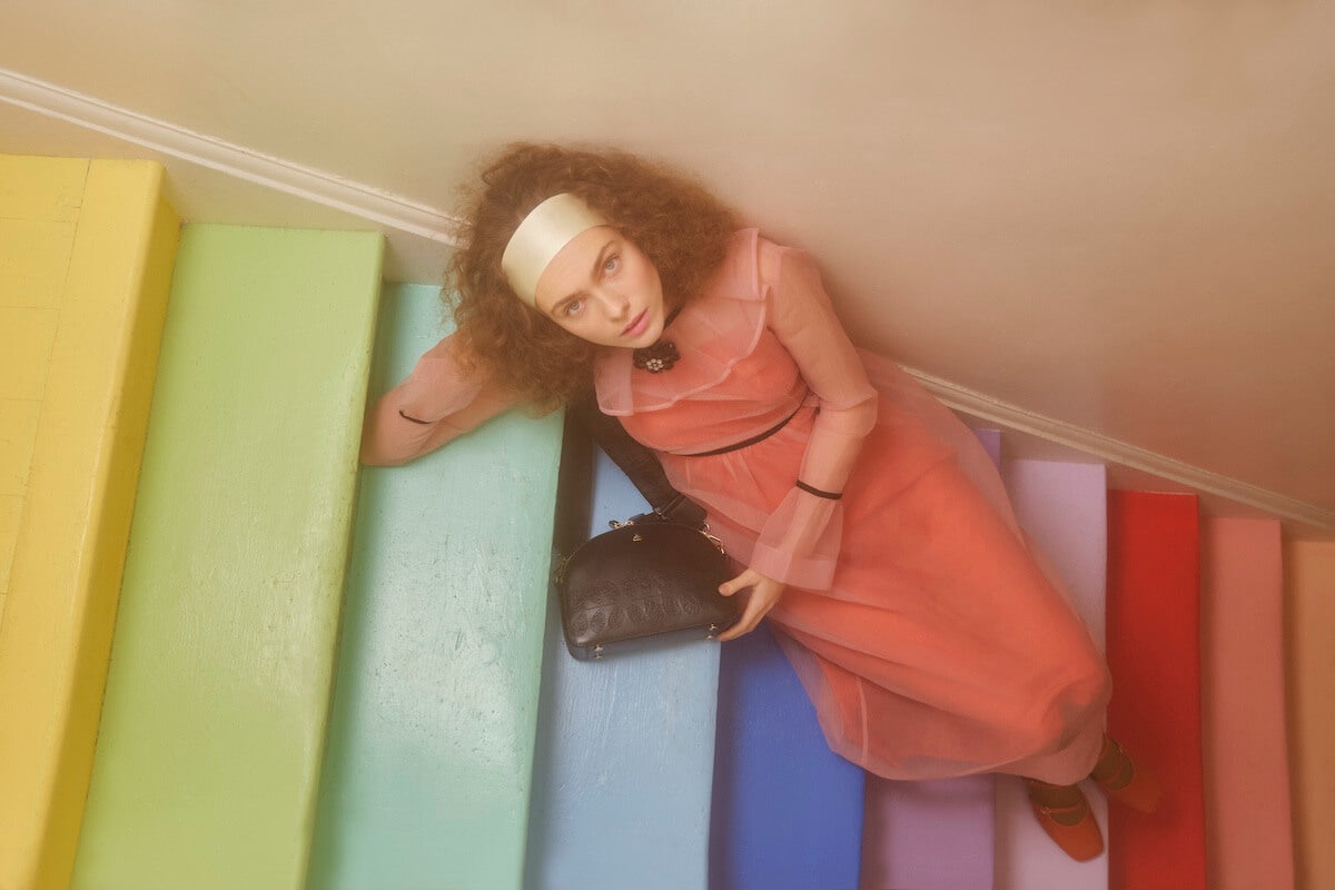 Model looking at someone on bright stairs with Orla Kiely bag 