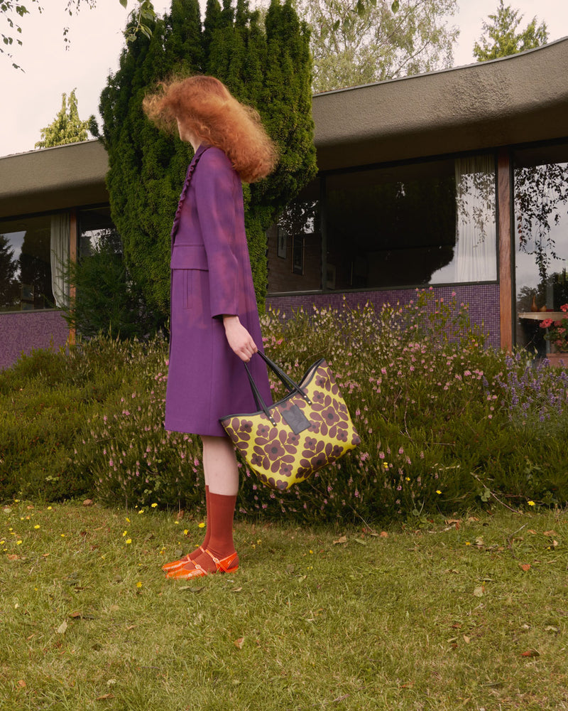 Woman holding a Flower Tile Tote Bag by Orla Kiely in a garden
