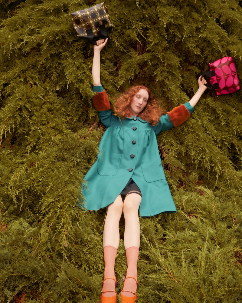 Person lying in tree with two Orla Kiely handbags