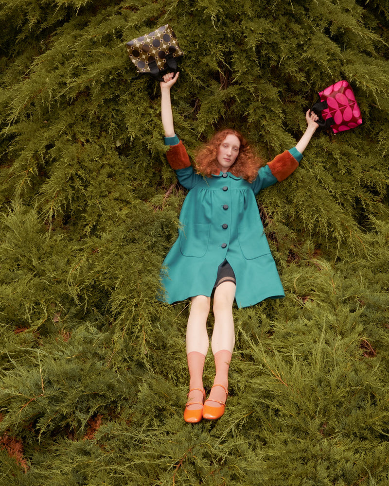 Person lying in tree with two Orla Kiely handbags