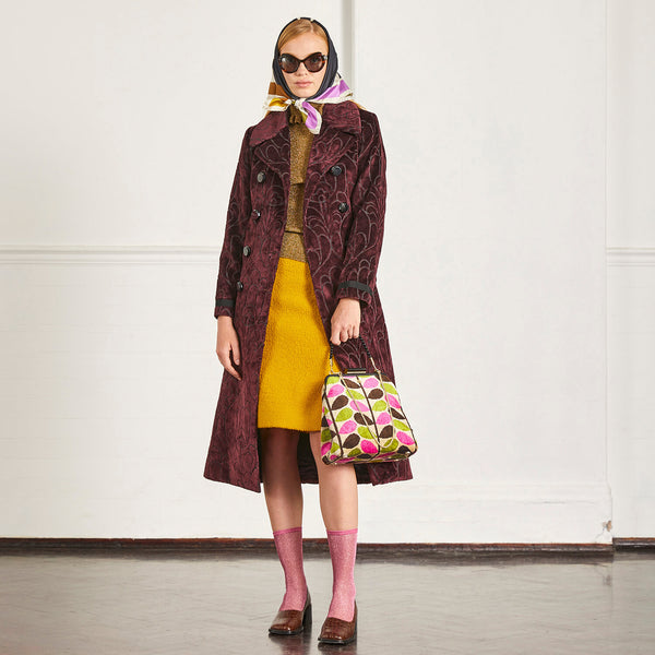 Model wearing an Orla Kiely Jenny D Velvet Handbag in Pink Multi Stem