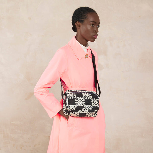 Model wearing the Angle Camera Bag in Lattice Flower Tile Onyx pattern by Orla Kiely