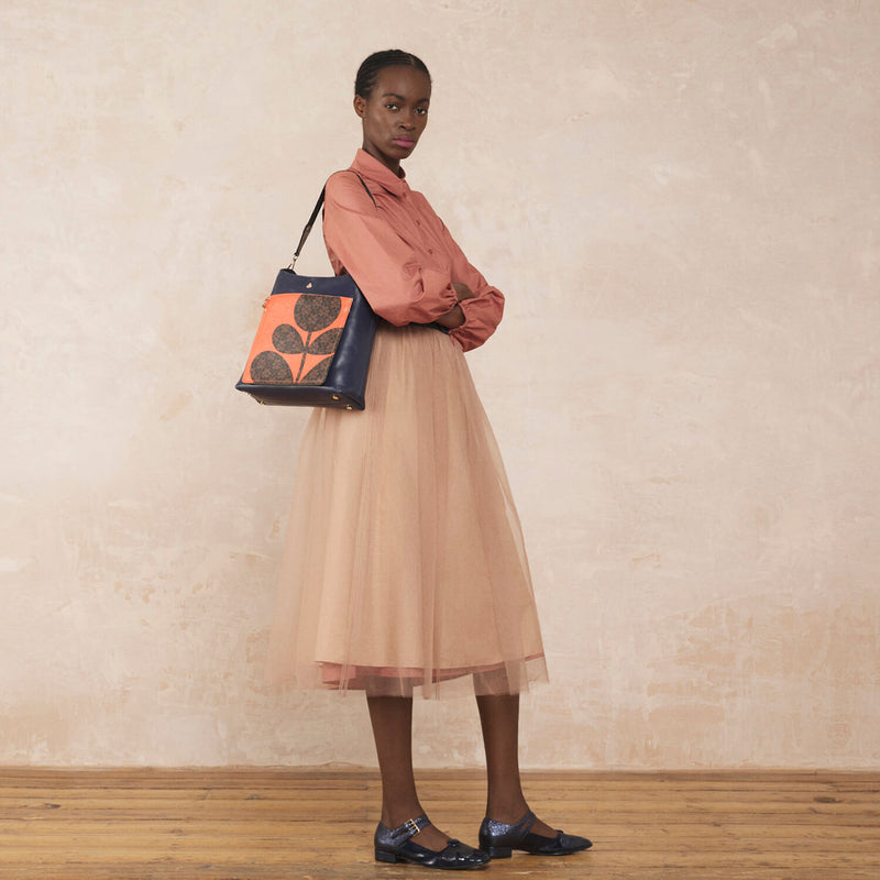 Model wearing the Carrymax Bucket Bag in Navy Puzzle Flower Emblem pattern by Orla Kiely