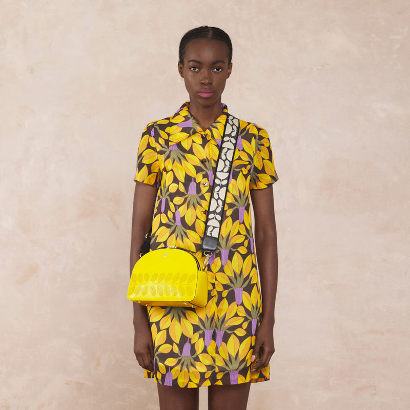 Model wearing the Luna Crossbody Handbag in Daffodil Punched Flower pattern by Orla Kiely