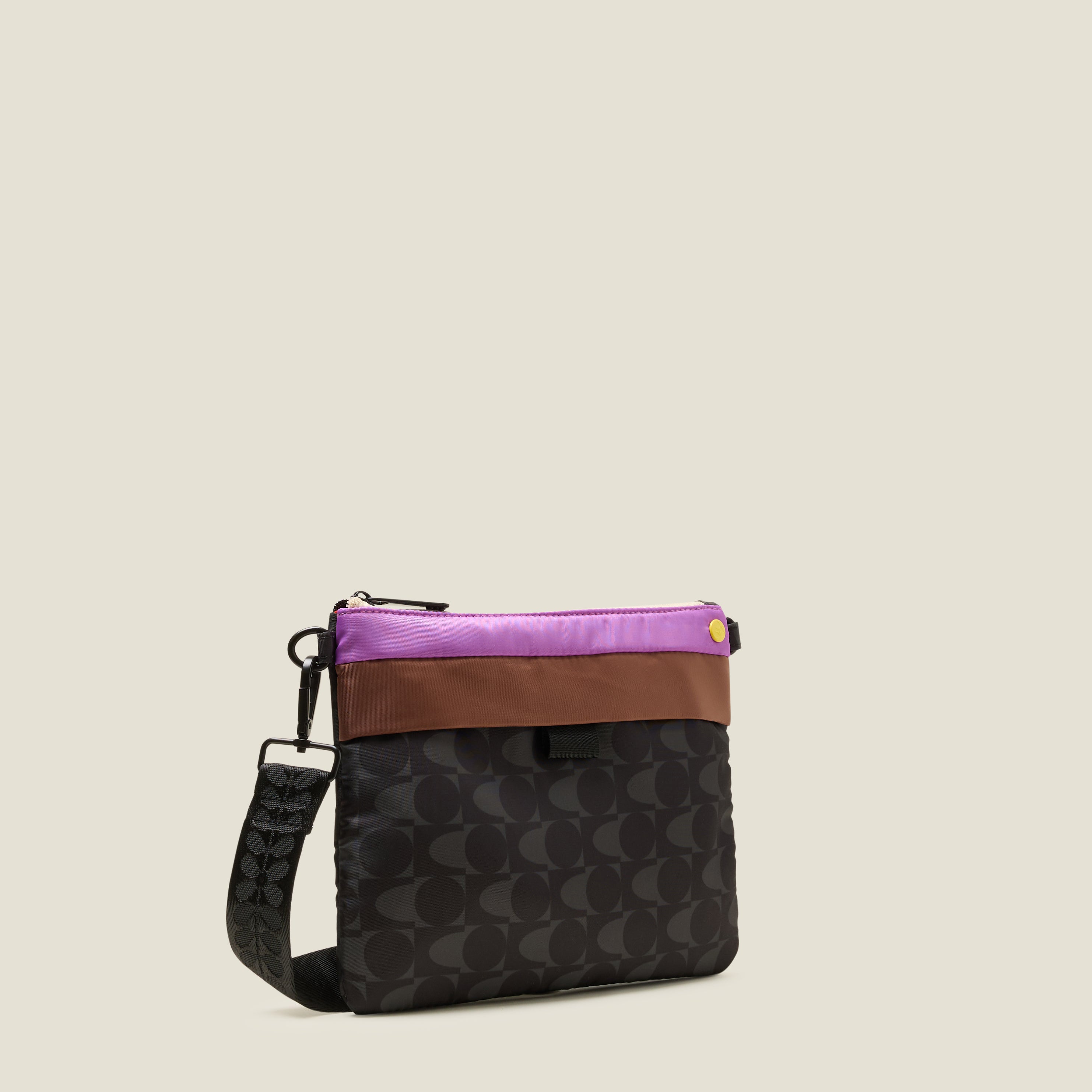 Multicolored Orla Kiely Quadrant crossbody bag with purple and brown contrast stripes with a black and grey print on a beige background