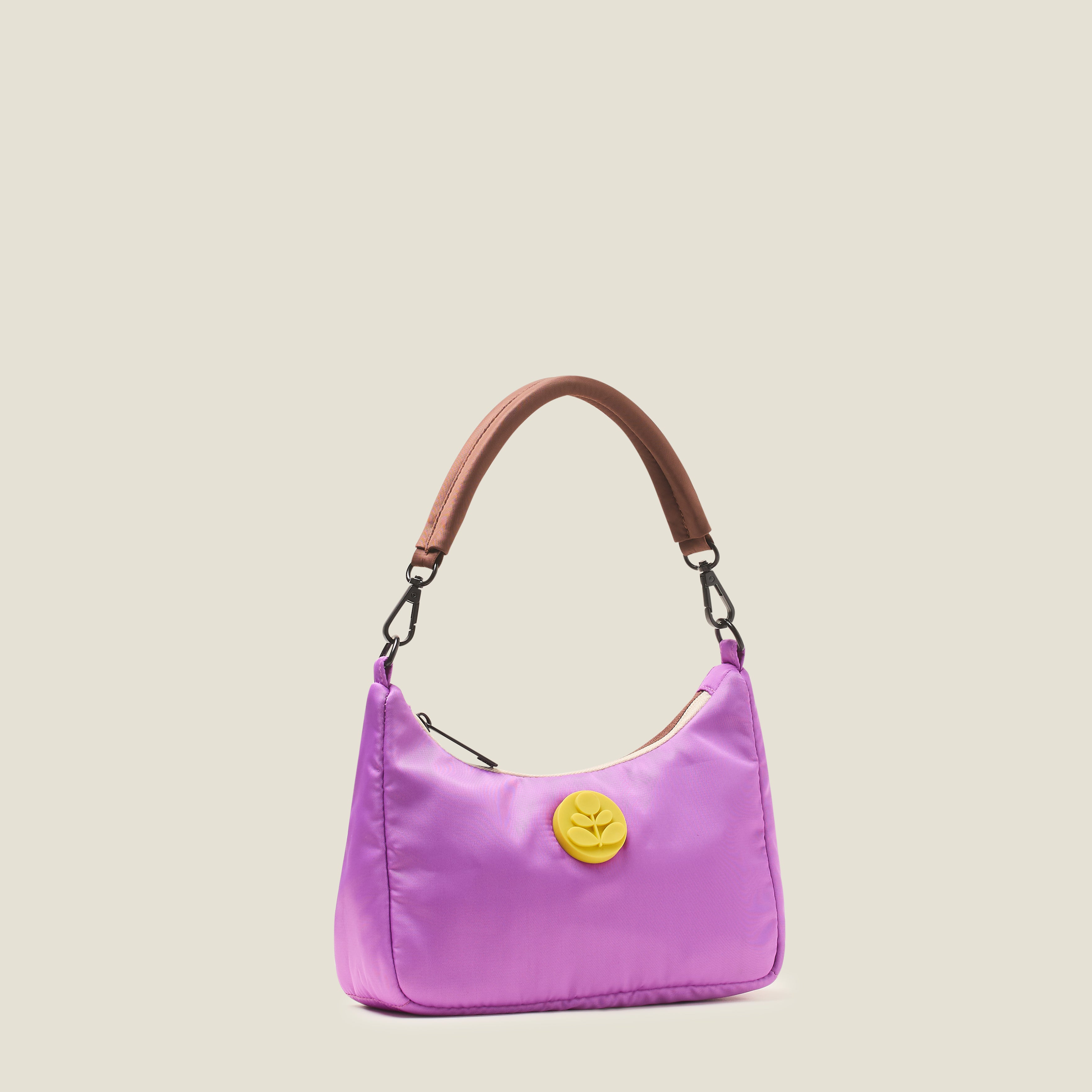 Side view of an over the shoulder handbag in lilac purple, featuring a yellow rubber Orla Kiely stem logo with brown carry handles on a beige background
