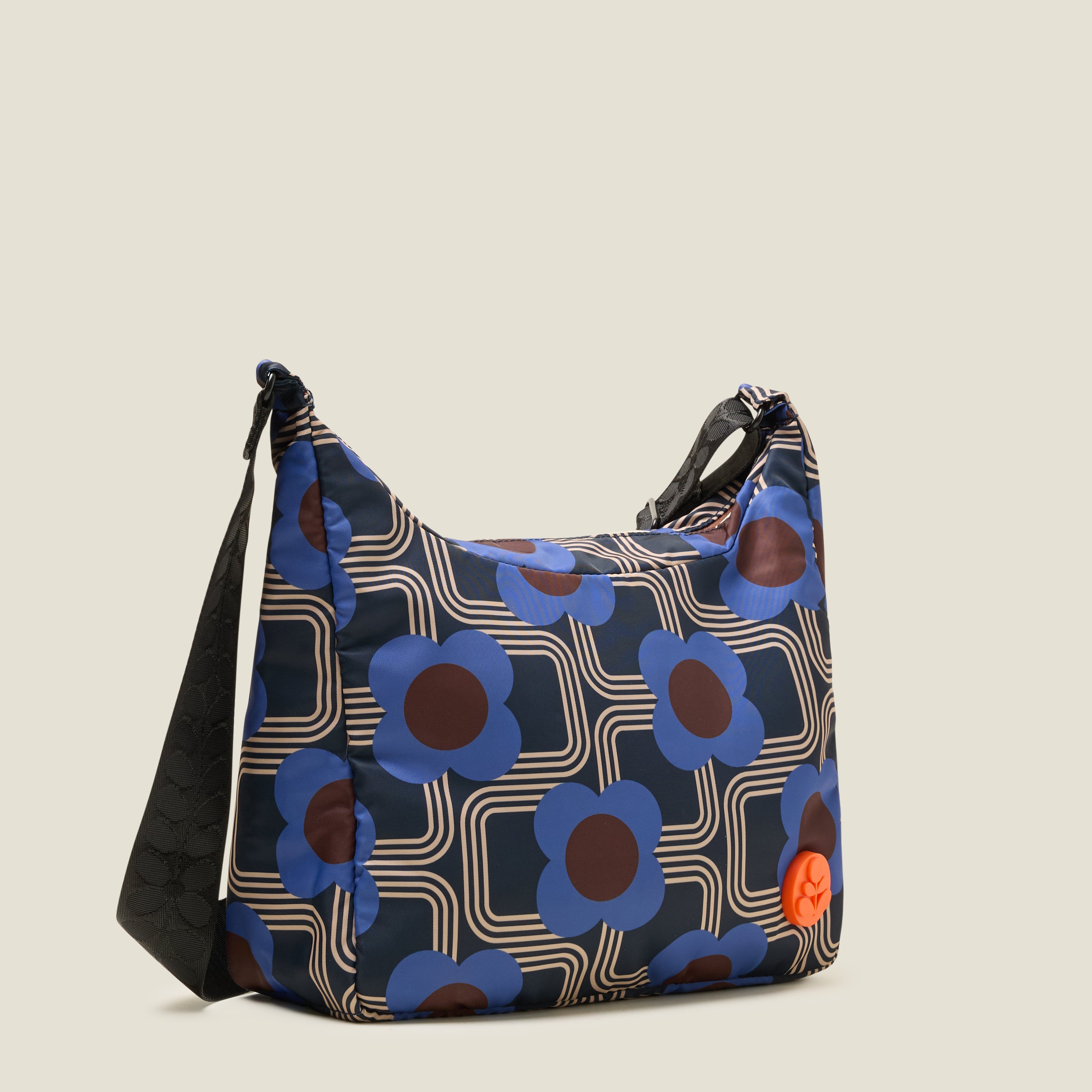 Side view of crossbody bag in an electric blue floral pattern. The handbag features a orange stem logo detail.