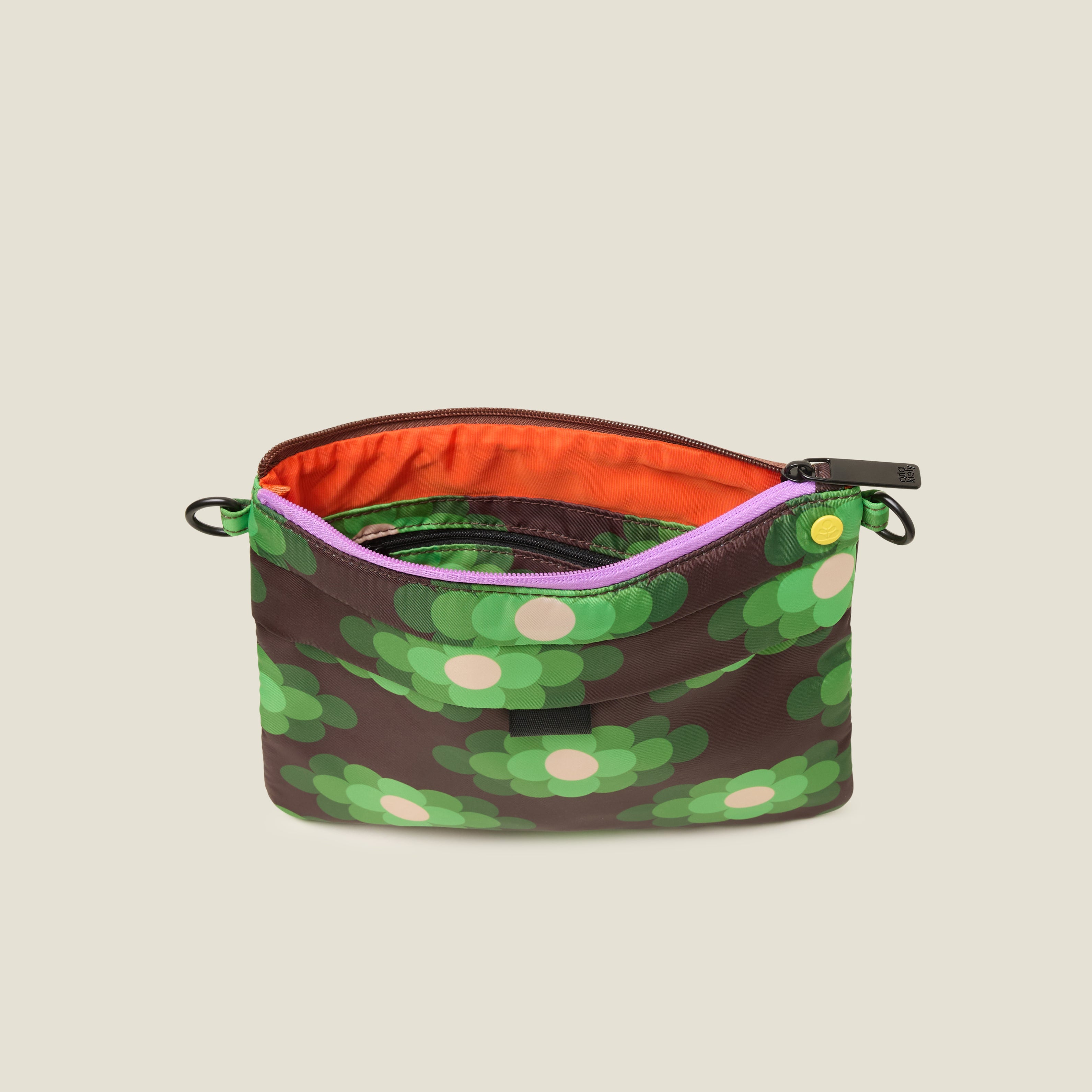 Green, brown, and cream patterned clutch bag with crossbody strap removed, top zipper is open to show orange lining