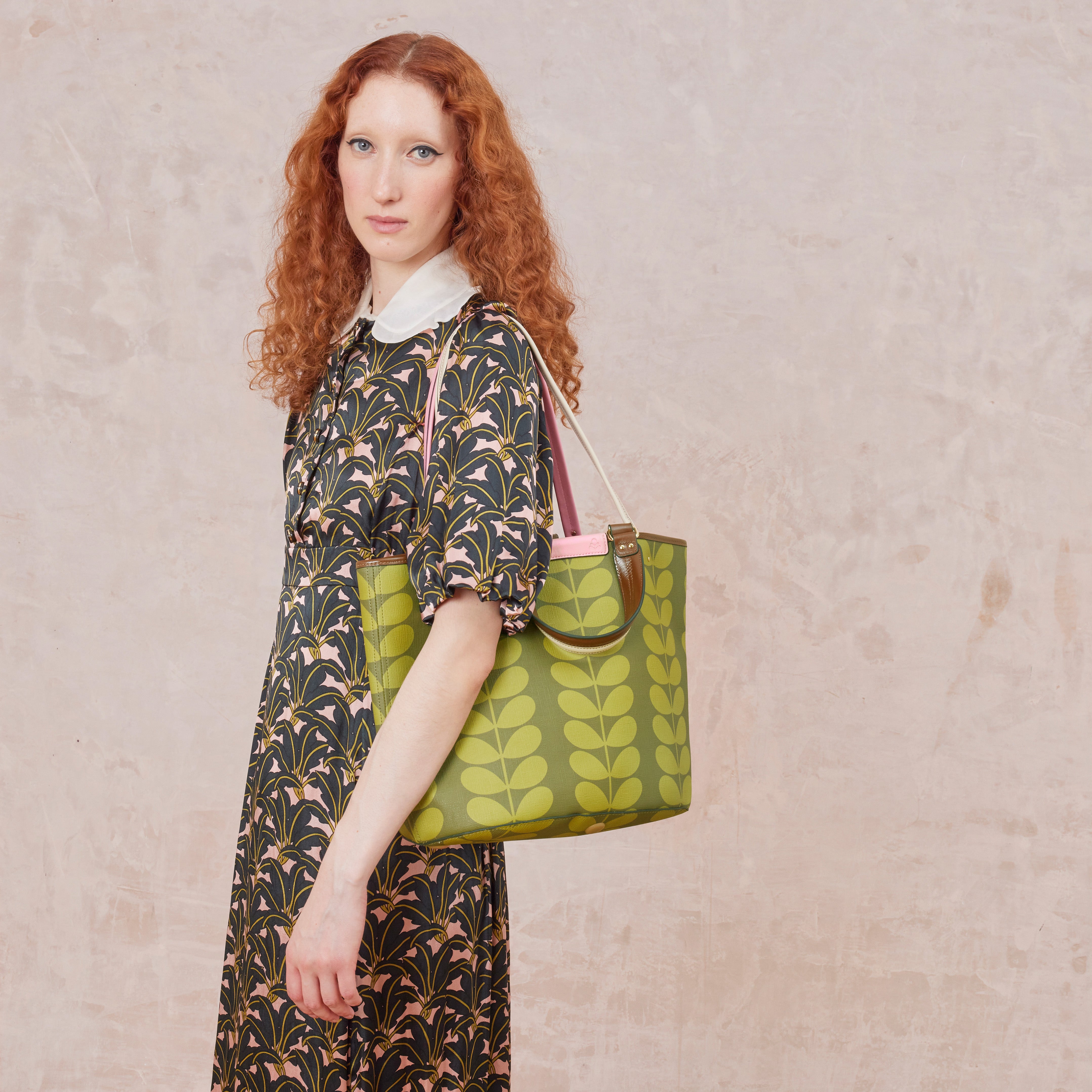 Olive green patterned smile tote bag worn over the shoulder by a women.