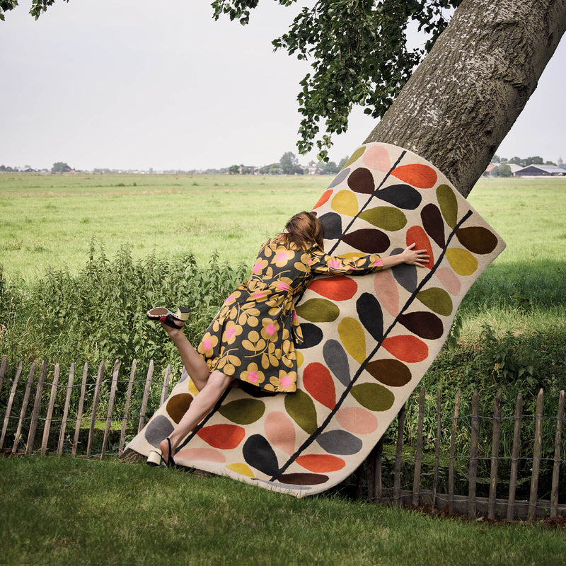 Model lying on an Orla Kiely Classic Multi Stem Rug