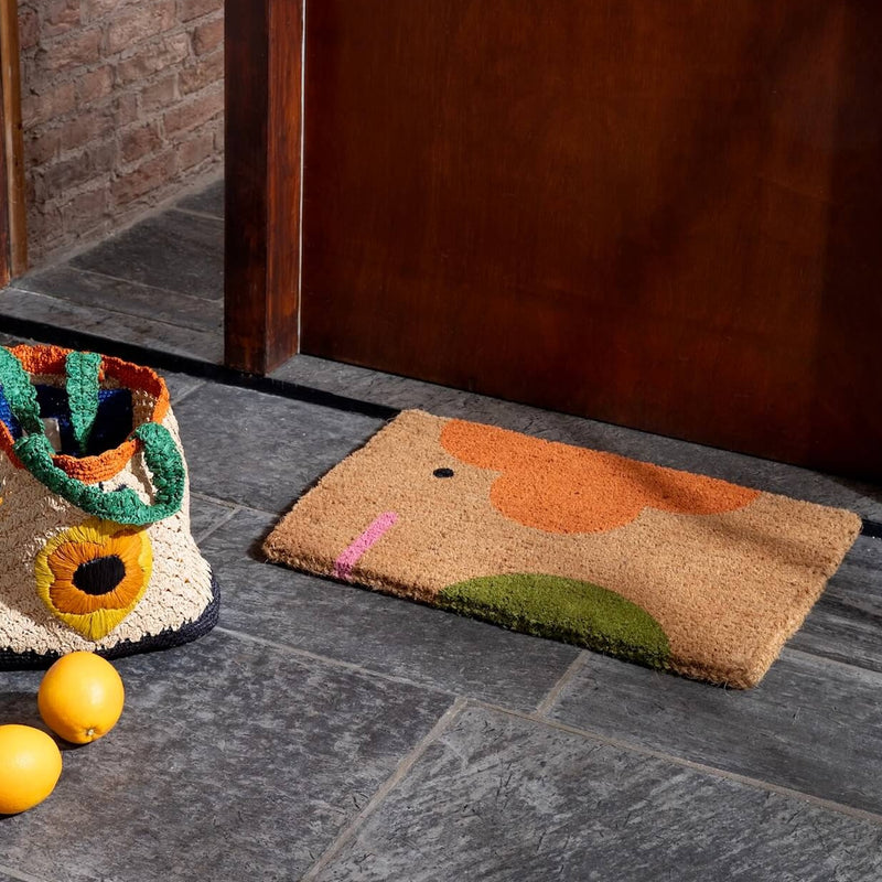 Lifestyle shot of an Orla Kiely elephant doormat next to a raffia bag