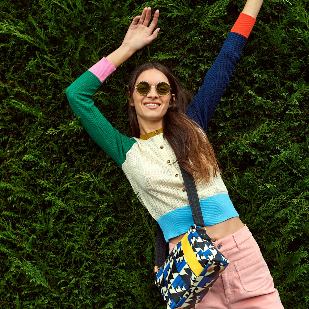 Dancing in front of a hedge with a toucan Orla Kiely bag