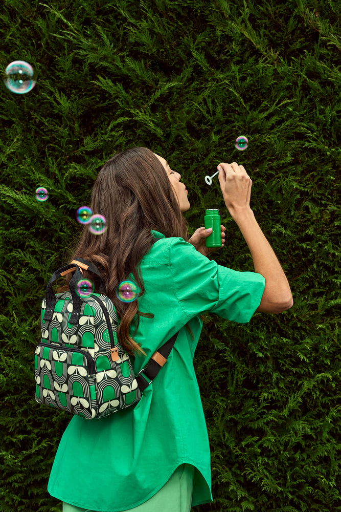 Person blowing bubbles with a Orla Kiely buddy backpack on