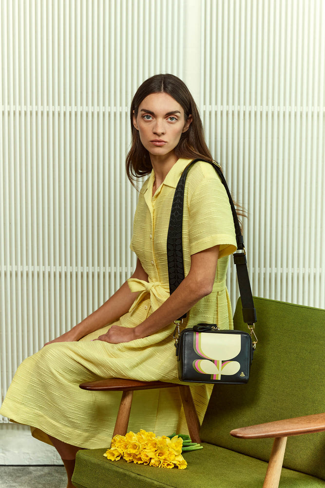 Sitting on a chair arm with an Orla Kiely bag 