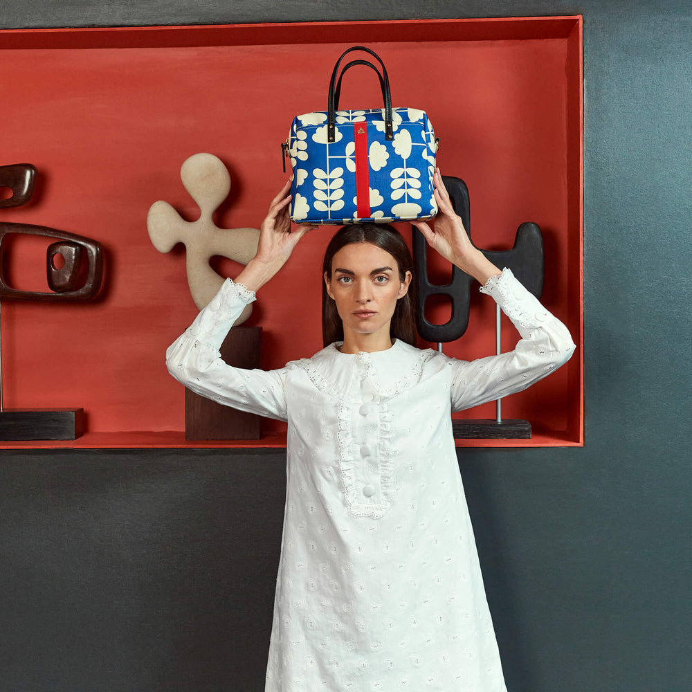 Balancing a blue Orla Kiely bag on their head