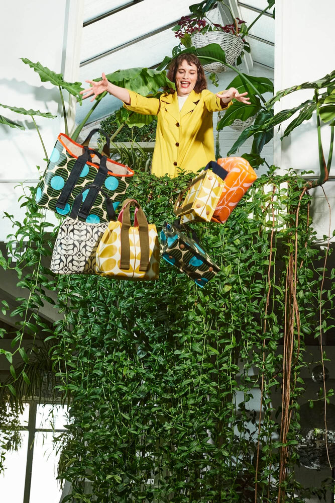 Person Dropping her Orla Kiely bags off a vine covered balcony