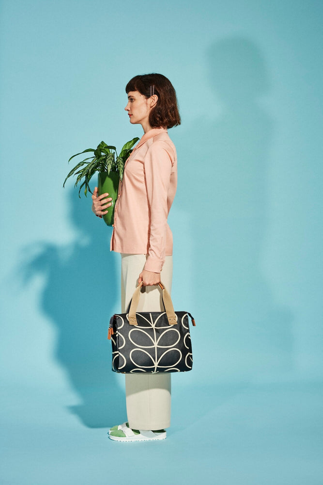 Person holding a plant and a linear stem liquorice handbag