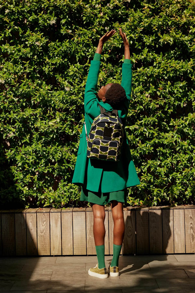 Stretching in front of a hedge with an Orla Kiely bestie backpack