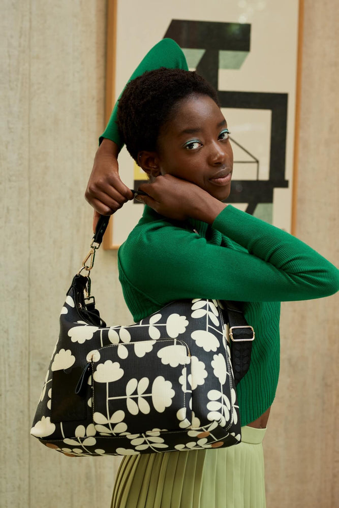 Person looking over their shoulder and their cut stem midi sling Orla Kiely bag