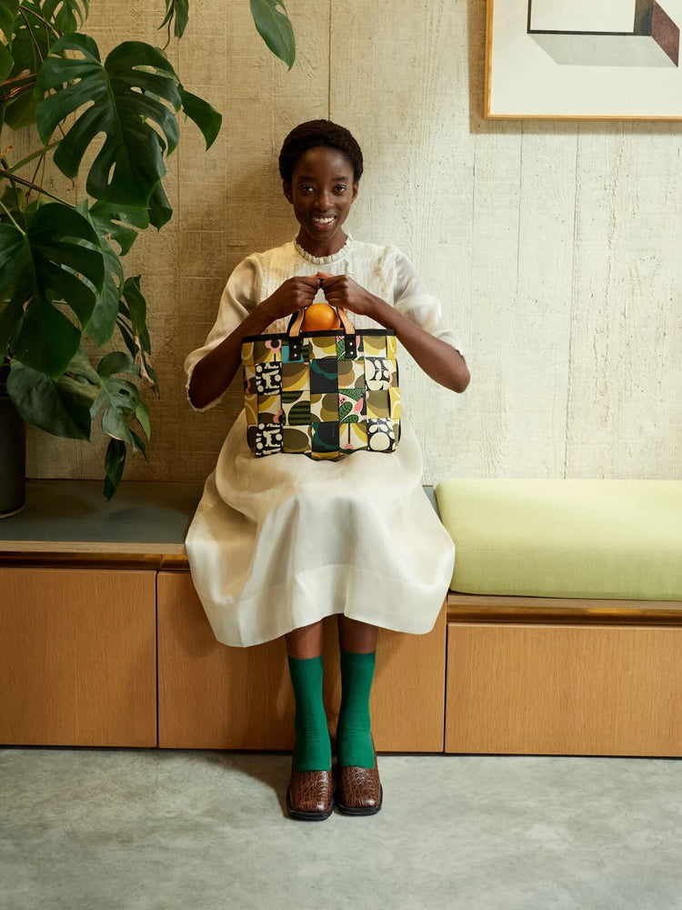 Sitting down with a woven waste basket Orla Kiely bag 