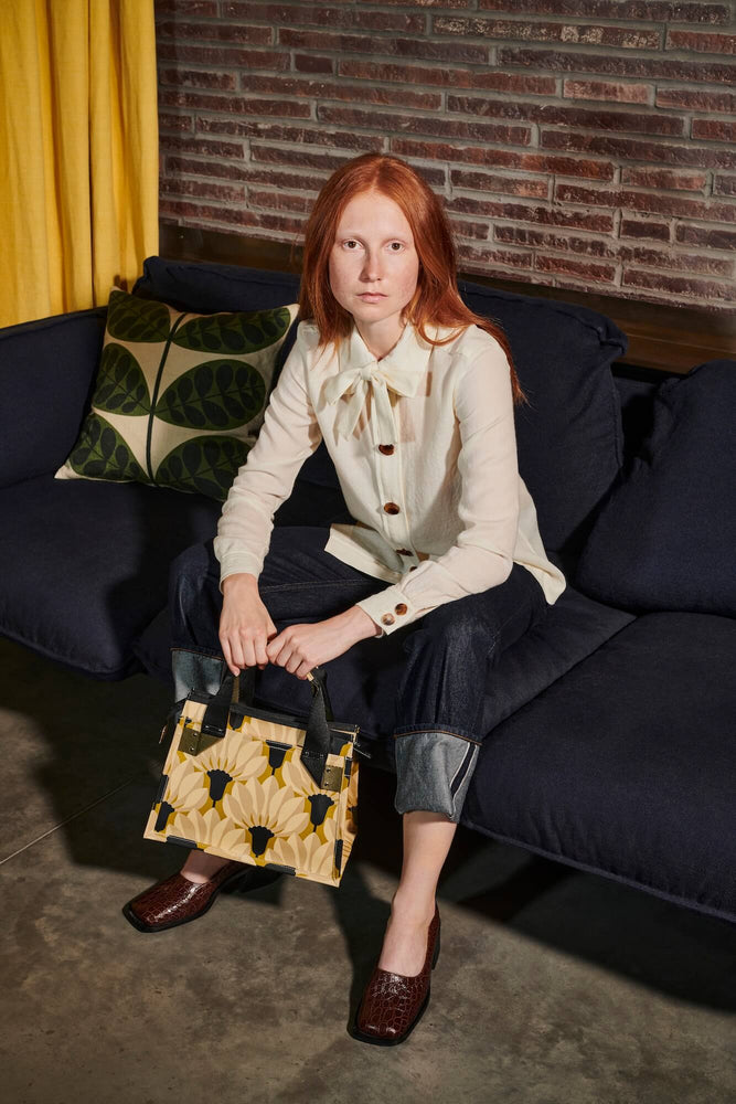 Red haired women with a yellow Orla Kiely bag and a botanica stem cushion