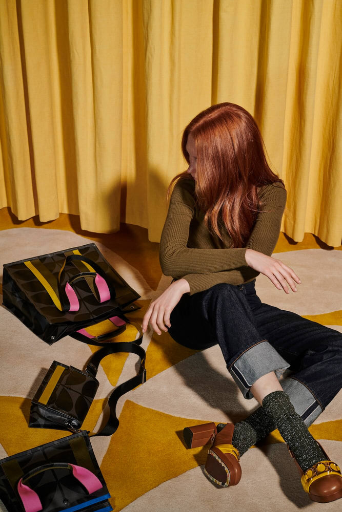 Model on a rug with three Orla Kiely bags 