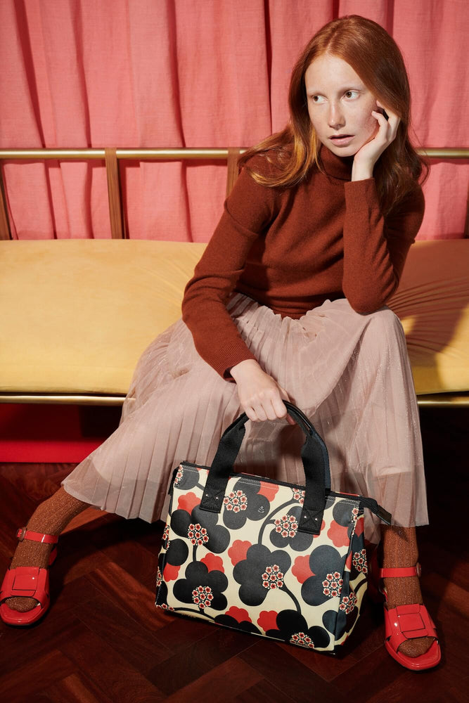 Women looking into the distance whilst holding an Orla Kiely bag 