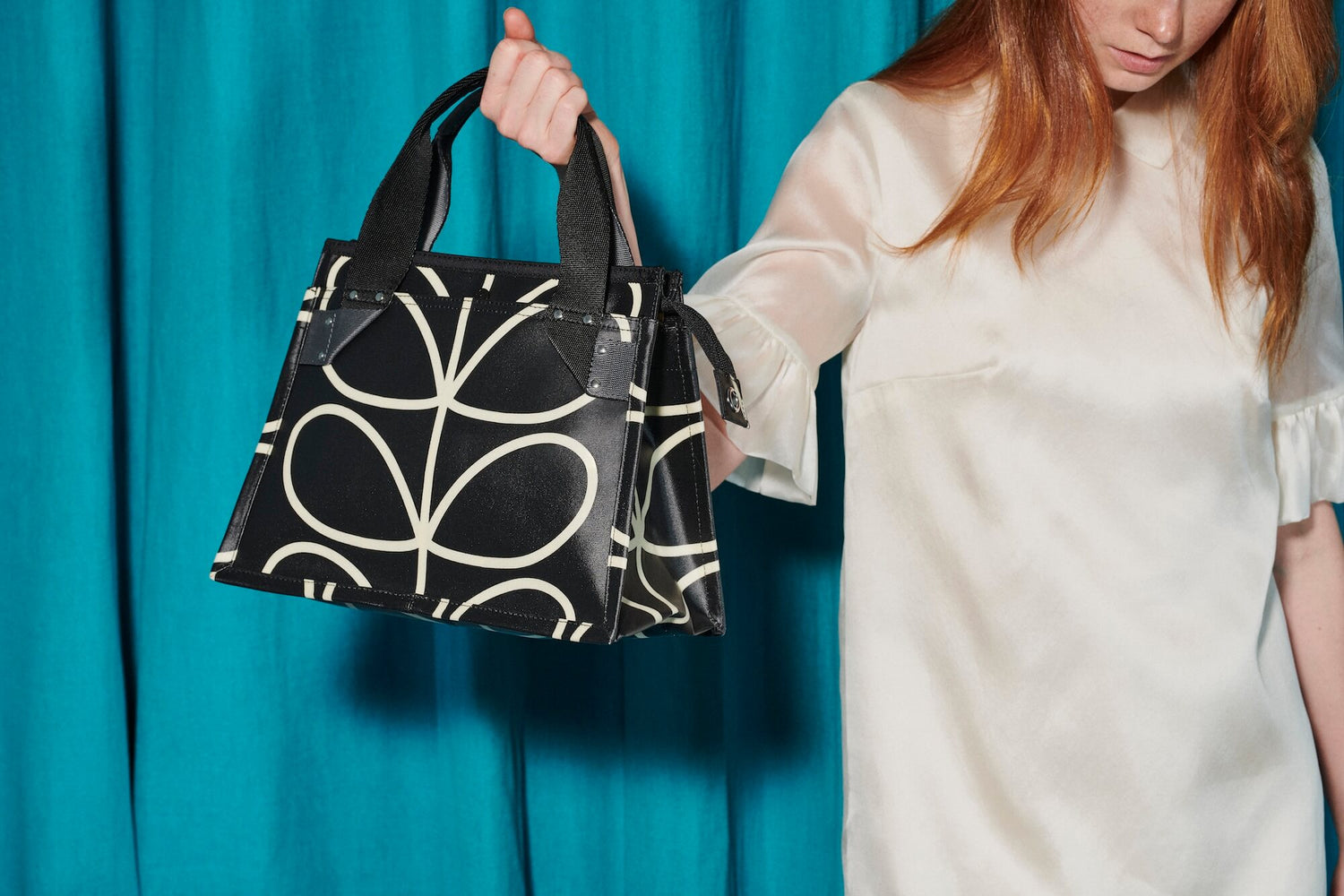 Woman in white holding black Orla Kiely liquorice stem bag