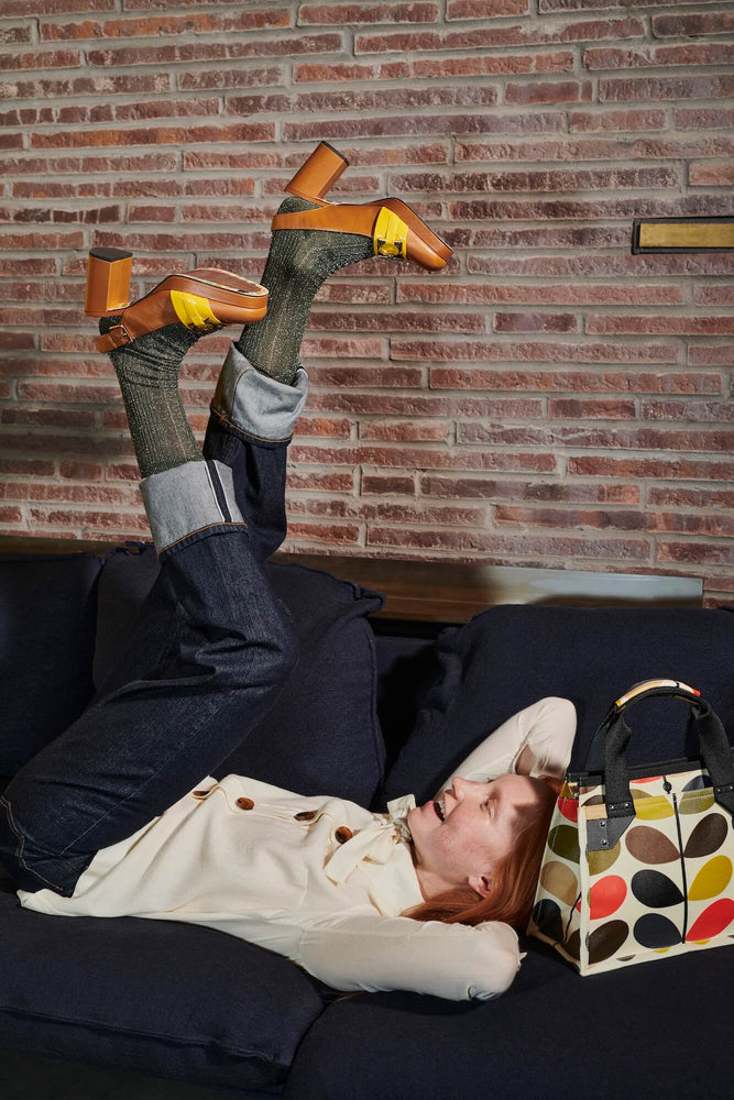 Model with her feet up and a multi stem Orla Kiely bag 