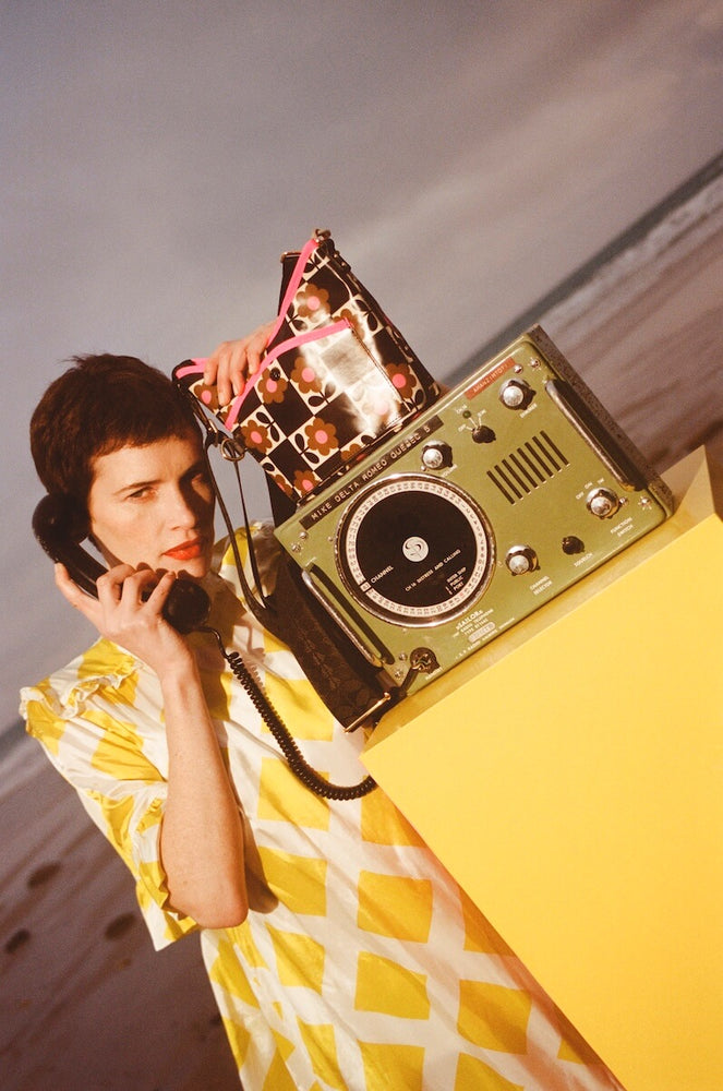 Model on the phone with a glossy Orla Kiely bag next to her