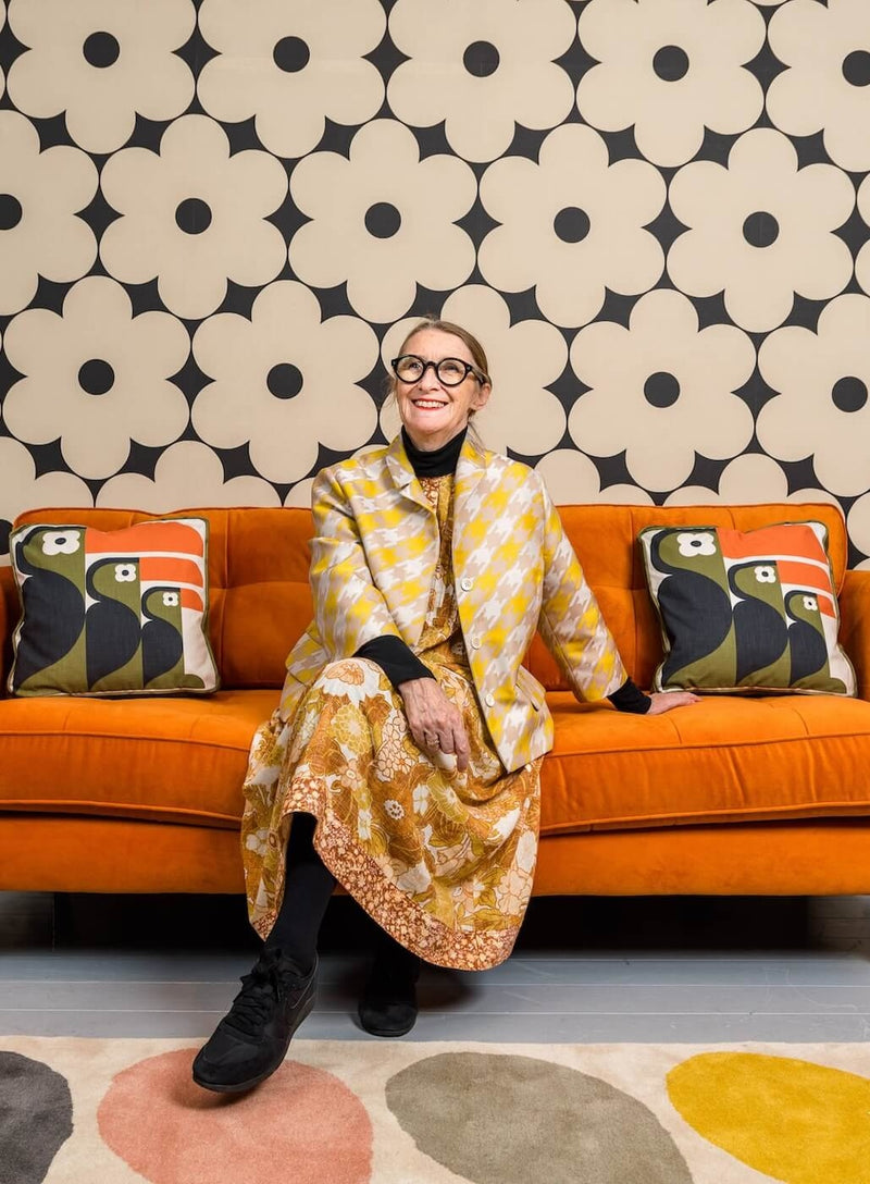 Orla Kiely sitting in front of a rug on an orange sofa